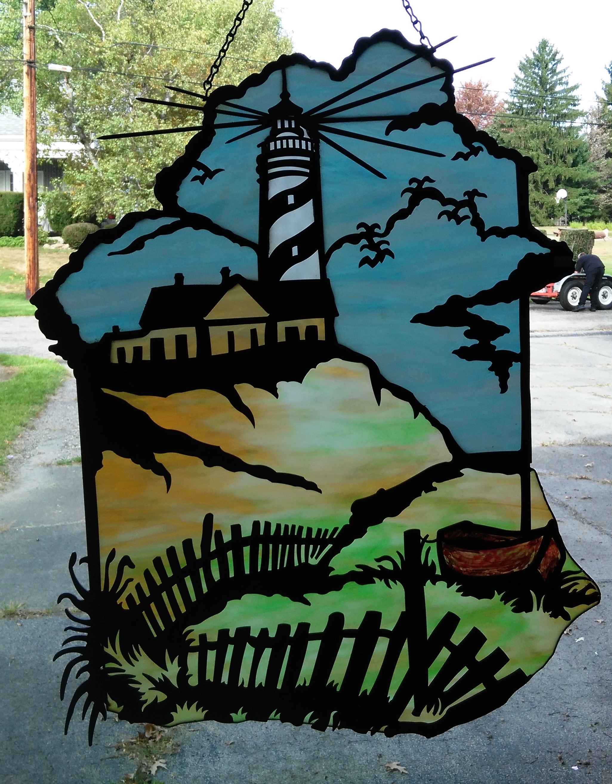 A glass piece hanging from a window with a haunted lighthouse portrait